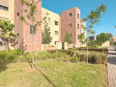 a large brick building with trees in front of it at Cocon Prestigia Argan avec piscine & parking in Marrakech
