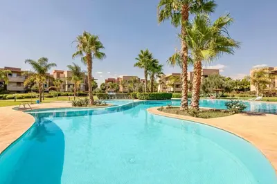 a large swimming pool with palm trees in a resort at RESIDENCE PRESTIGIA, Piscine, calme et verdure in Marrakech