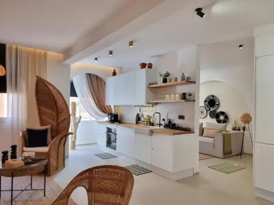 a kitchen with white cabinets and a living room at Bohemian & Moroccan Apartment Close to Airport & Medina in Marrakech