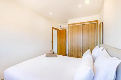 a bedroom with a white bed and a wooden door at Escapade intime en ville rouge in Marrakech