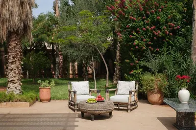 a patio with two chairs and a table and trees at Villa Yali in Marrakech