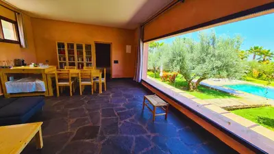 a room with a large window with a table and a pool at Villa Deneb - secret garden, swimming pool and starry sky in Marrakech