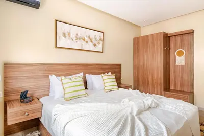 a bedroom with a white bed with a wooden headboard at Idéal Famille Neuf - Fibre Optique - 7 min Guéliz in Marrakech