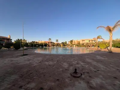 a large pool of water with palm trees and buildings at La perle de la palmeraie in Marrakech