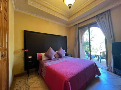 a bedroom with a large bed with a pink bedspread at La perle de la palmeraie in Marrakech