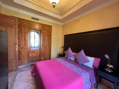 a bedroom with a large bed with a pink blanket at La perle de la palmeraie in Marrakech