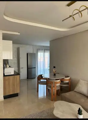 a living room with a table and a kitchen at Residence hôte standing Marrakech Gueliz in Marrakech