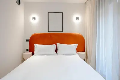 a white bed with an orange headboard in a room at Premium Hospitality - Hivernage Marrakech in Marrakech