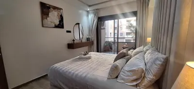 a bedroom with a bed with pillows and a window at Appartement Moderne Centre Gueliz Sunny Pool PS4 & Wi-Fi in Marrakech