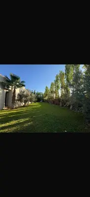 a large field of grass with a house and trees at Villa Alya in Marrakech