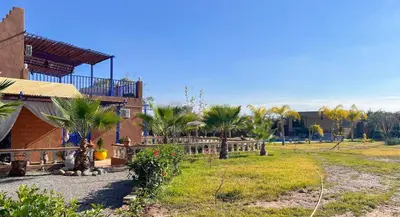 a house with a yard with palm trees and a fence at Charming Family Villa with Private Pool & Garden - Near Marrakech in Sraïri