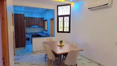 a kitchen and dining room with a wooden table and chairs at Appartement Aéroport Marrakech Rest in Marrakech