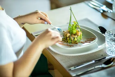 a woman sitting at a table eating a plate of food at Villa Tacai in Graoua