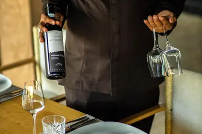 a man pouring a bottle of wine into a glass at Villa Tacai in Graoua