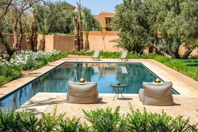 a swimming pool with two chairs and a table at Villa Tacai in Graoua