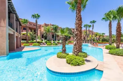 a swimming pool with palm trees in a resort at appartement avec piscine et charme marocain in Marrakech