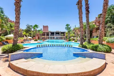 a large swimming pool in a resort with palm trees at appartement avec piscine et charme marocain in Marrakech