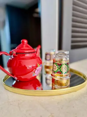 a red tea pot and a glass on a tray at appartement avec piscine et charme marocain in Marrakech