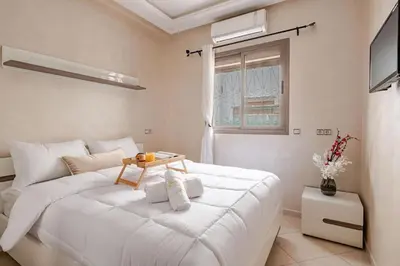a bedroom with a white bed with a table on it at Moroccan Comfort & Charm - 10 min from Guéliz in Marrakech