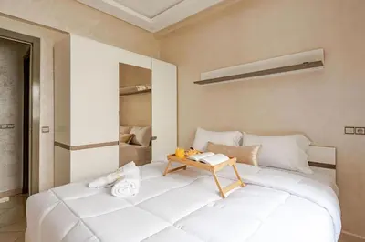 a bedroom with a large white bed with a table on it at Moroccan Comfort & Charm - 10 min from Guéliz in Marrakech