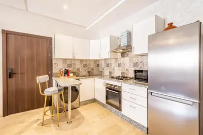 a kitchen with white cabinets and a stainless steel refrigerator at Cozy and comfortable appartement in Marrakech