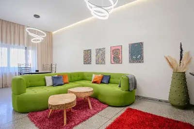 a living room with a green couch and a red rug at 2BR Art Deco Loft - Central Gueliz Marrakech in Marrakech