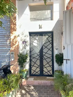 a black door on a white house with plants at Modern apartment in the heart of Marrakech, just 9 minutes from the airport in Marrakech