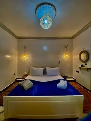 a bedroom with a large bed with a blue blanket at Dar Koutobia Stars in Marrakech