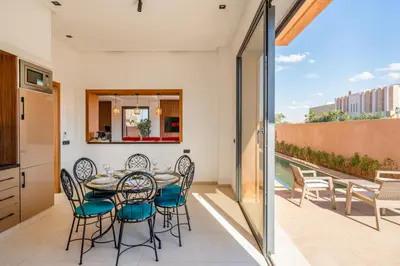 a dining room with a table and chairs on a balcony at Luxury 5-Suite Villa with private pool in GOLF Amlkis ,free Airport transport service in Marrakech
