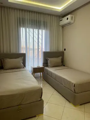 two beds in a hotel room with a window at M&O airport appartment in Marrakech