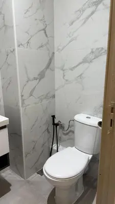 a white bathroom with a toilet and a shower at M&O airport appartment in Marrakech