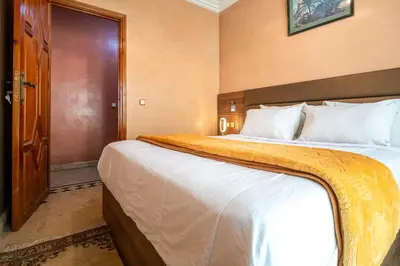 a hotel room with a large bed and a door at Résidence Qodwa in Marrakech