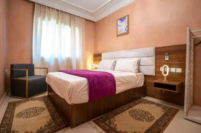 a bedroom with a bed and a chair and a window at Résidence Qodwa in Marrakech