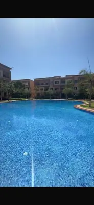 a large pool of blue water in front of a building at Marrakech résidence Nour 6 in Marrakech