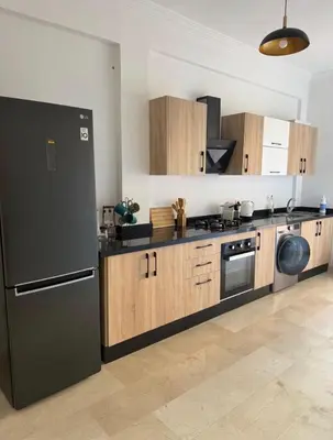 a kitchen with a black refrigerator and wooden cabinets at Marrakech résidence Nour 6 in Marrakech