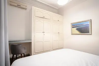 a white bedroom with a bed and a chair at Art Deco Loft 1BR Central Guéliz Marrakech in Marrakech