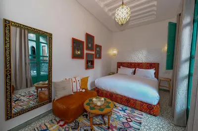 a bedroom with a bed and a mirror and a table at Riad Nejma Benyoussef in Marrakech
