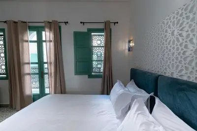 a bedroom with a white bed and two windows at Riad Nejma Benyoussef in Marrakech