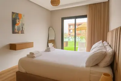 a bedroom with a large white bed with a window at Évasion à Marrakech confort, verdure et piscine in Marrakech