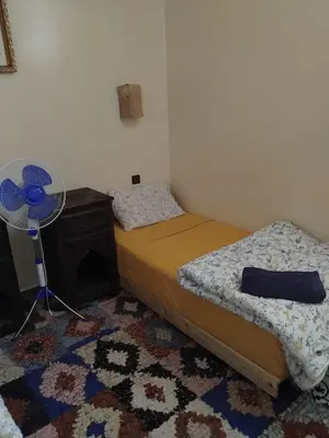 a bedroom with two beds and a fan and a rug at Dar Kawtar in Marrakech