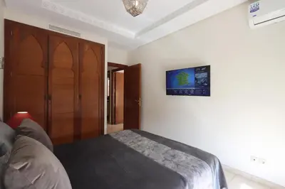 a bedroom with a bed and a tv on the wall at Apartment in the Heart of Marrakech 5th Floor in Marrakech