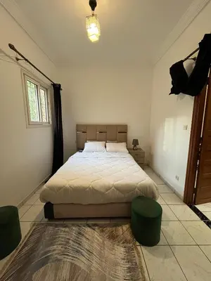 a bedroom with a bed and two ottomans at Riad Flouris in marrakech in Marrakech