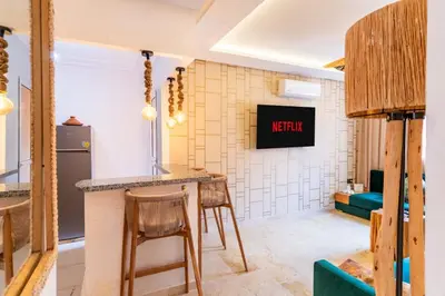 a kitchen and living room with a counter and stools at Suite Elegante 2 chambres Confort & Style Marrakech in Oulad Akkou