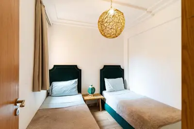 a bedroom with two beds and a chandelier at Suite Elegante 2 chambres Confort & Style Marrakech in Oulad Akkou