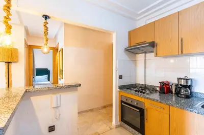 a kitchen with wooden cabinets and a counter top at Suite Elegante 2 chambres Confort & Style Marrakech in Oulad Akkou