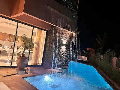 a swimming pool with a waterfall in front of a house at luxury 5 bedroom home in Marrakech
