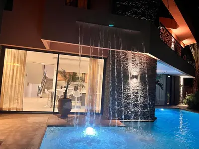 a swimming pool with a fountain in front of a building at luxury 5 bedroom home in Marrakech