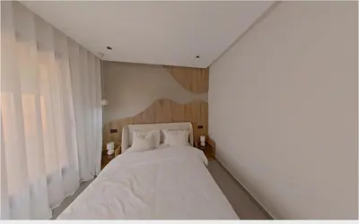 a bedroom with a bed with white sheets and a window at Appartement chic Menara Mall piscine Rooftop in Marrakech