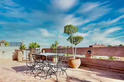 a table and chairs on a balcony with a tree at 1 King BR with AC, Roof Pool & View-Perfect for 2- City Center in Marrakech