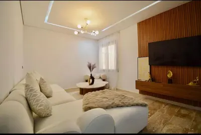 a living room with a white couch and a flat screen tv at Elegant Luxury Apartment in Marrakech